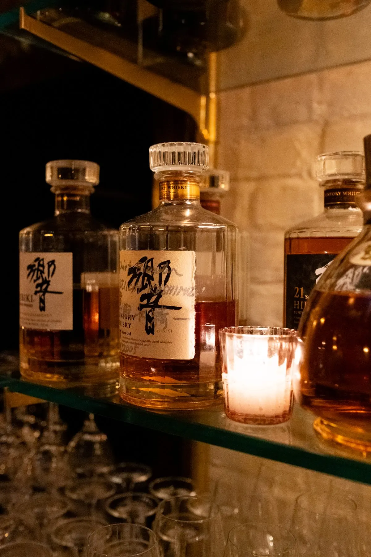 Hibiki bottles on a glass shelf by a candle
