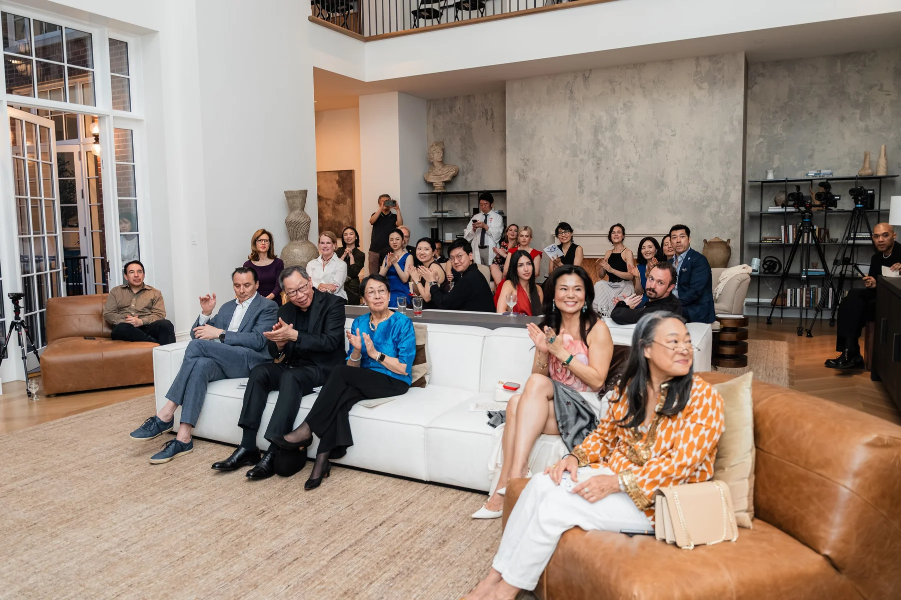 Guests on the sofas at the townhouse salon, applauding
