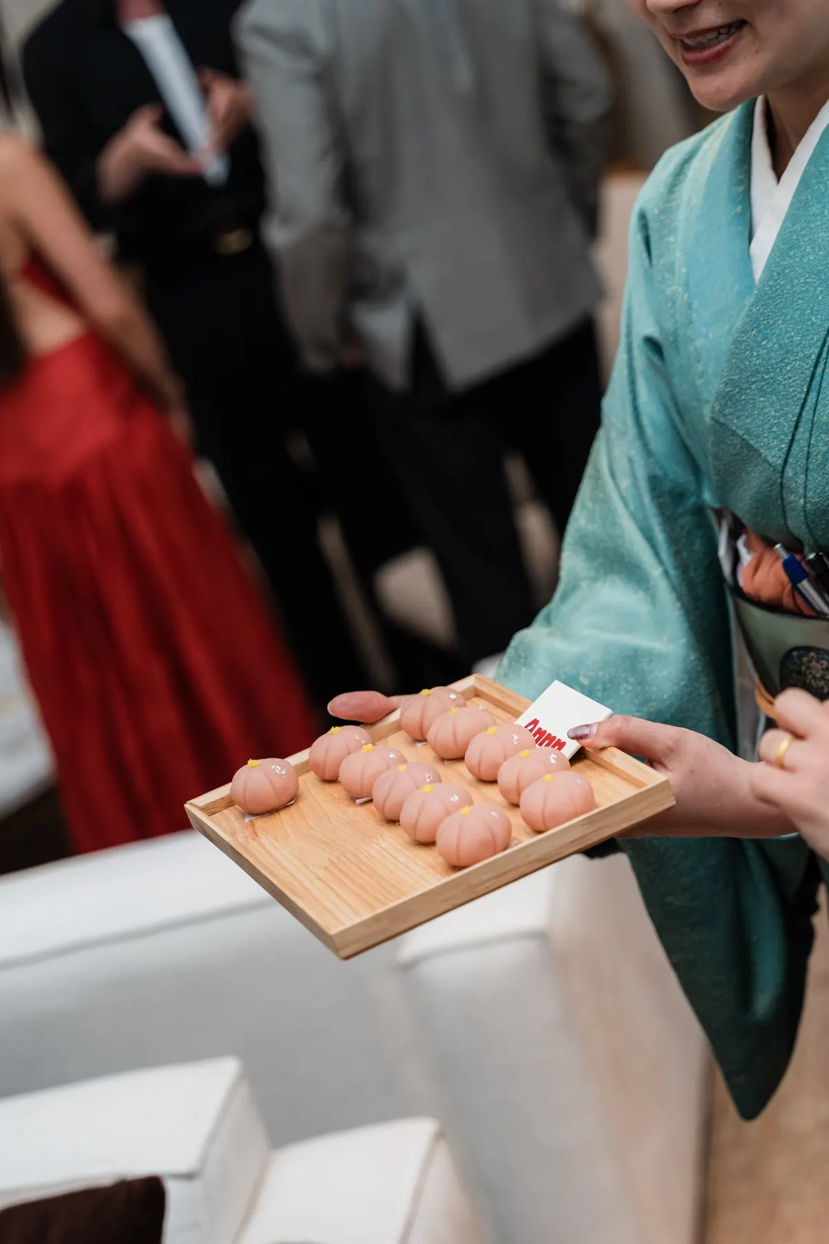 Wagashi on a wooden tray, offered by a host in kimono