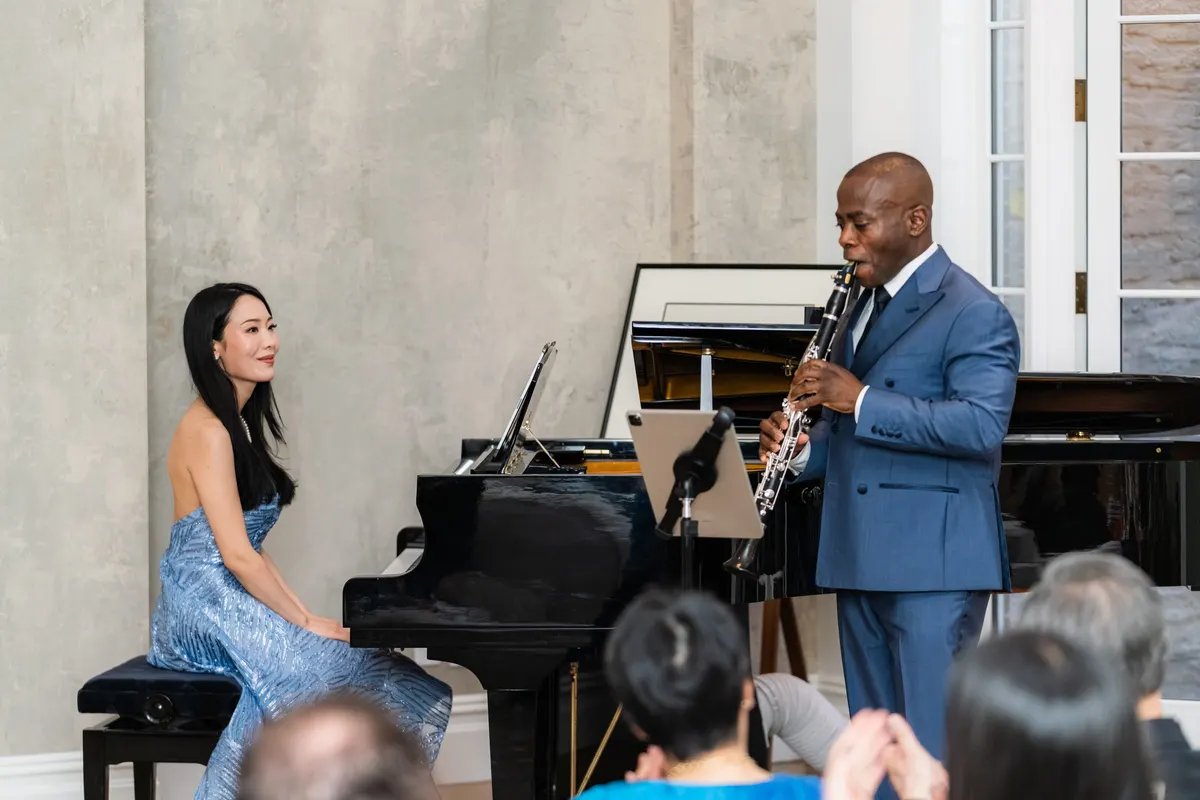 Rieko at the piano, smiling across at Anthony McGill as he plays